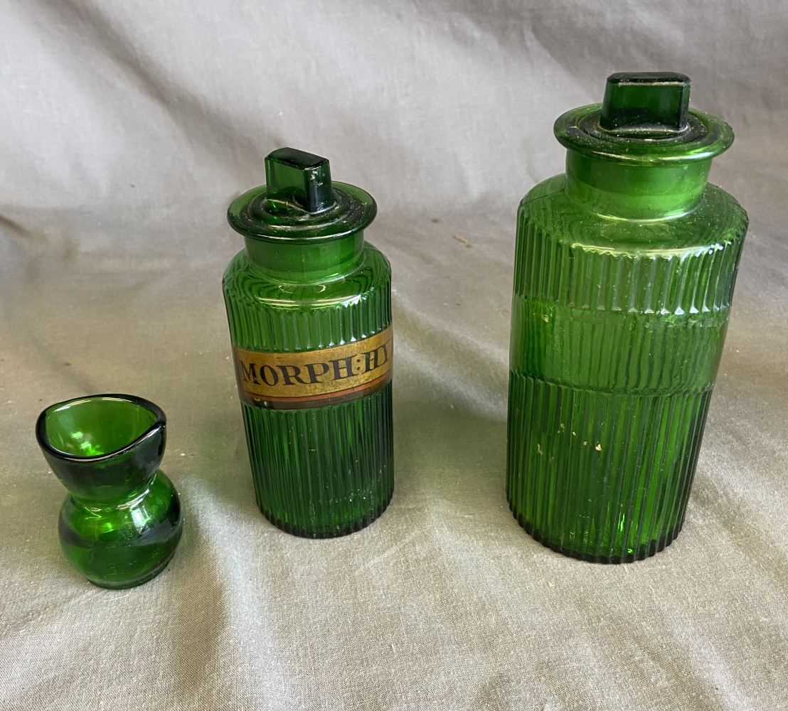 Green apothecary bottles and small measuring vessel