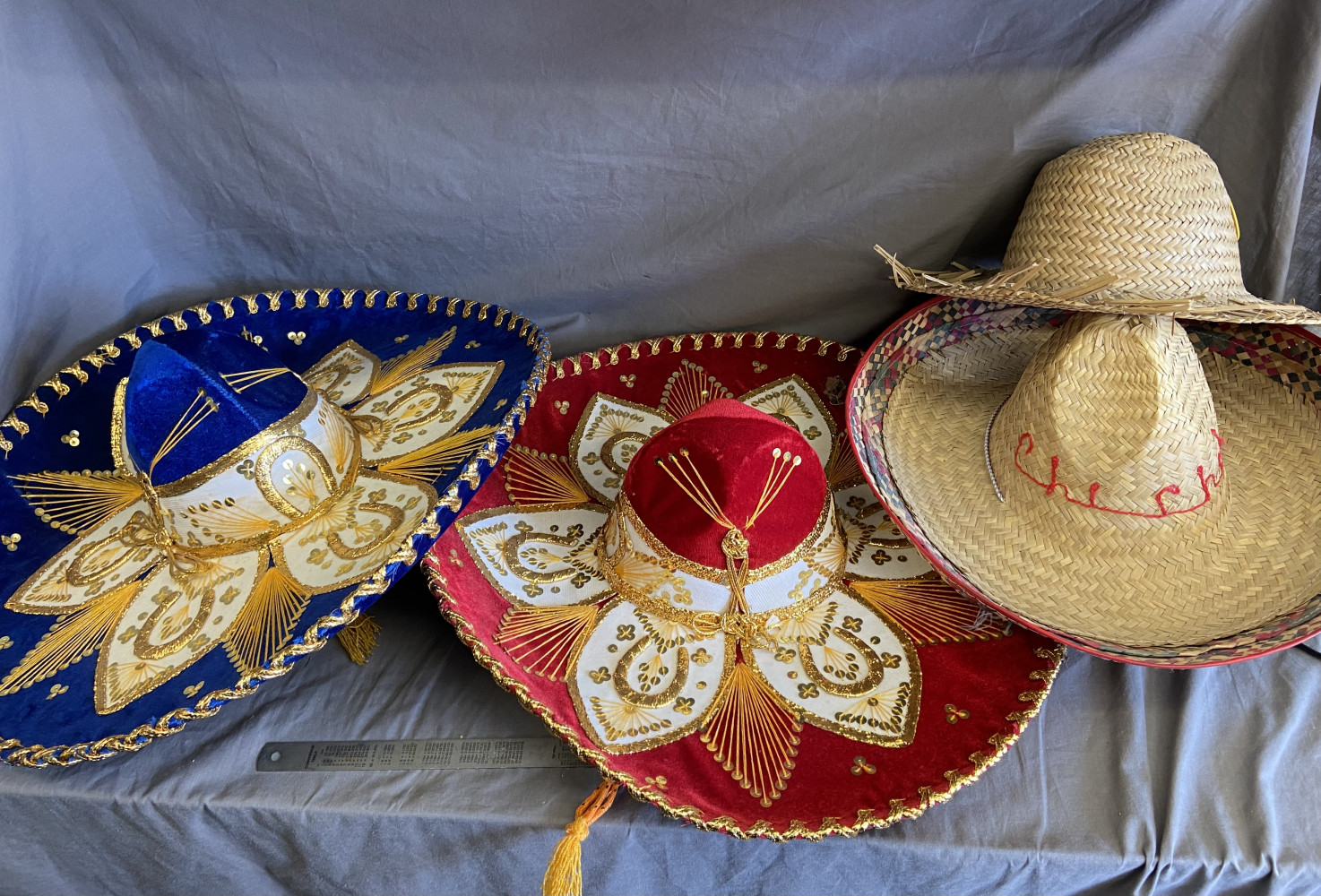 Two ornate Mexican sombreros and two straw hats