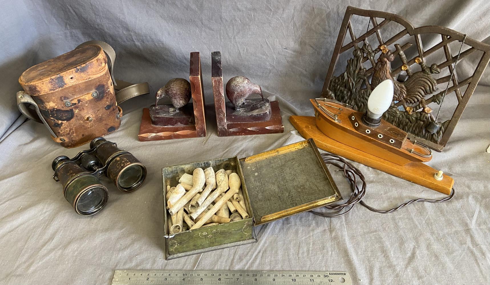 Binoculars in case, book ends, box of clay pipes, boat light and book stand