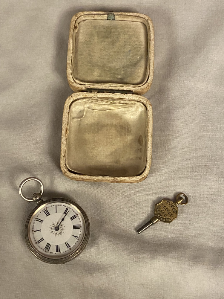 Small silver pocket watch with key