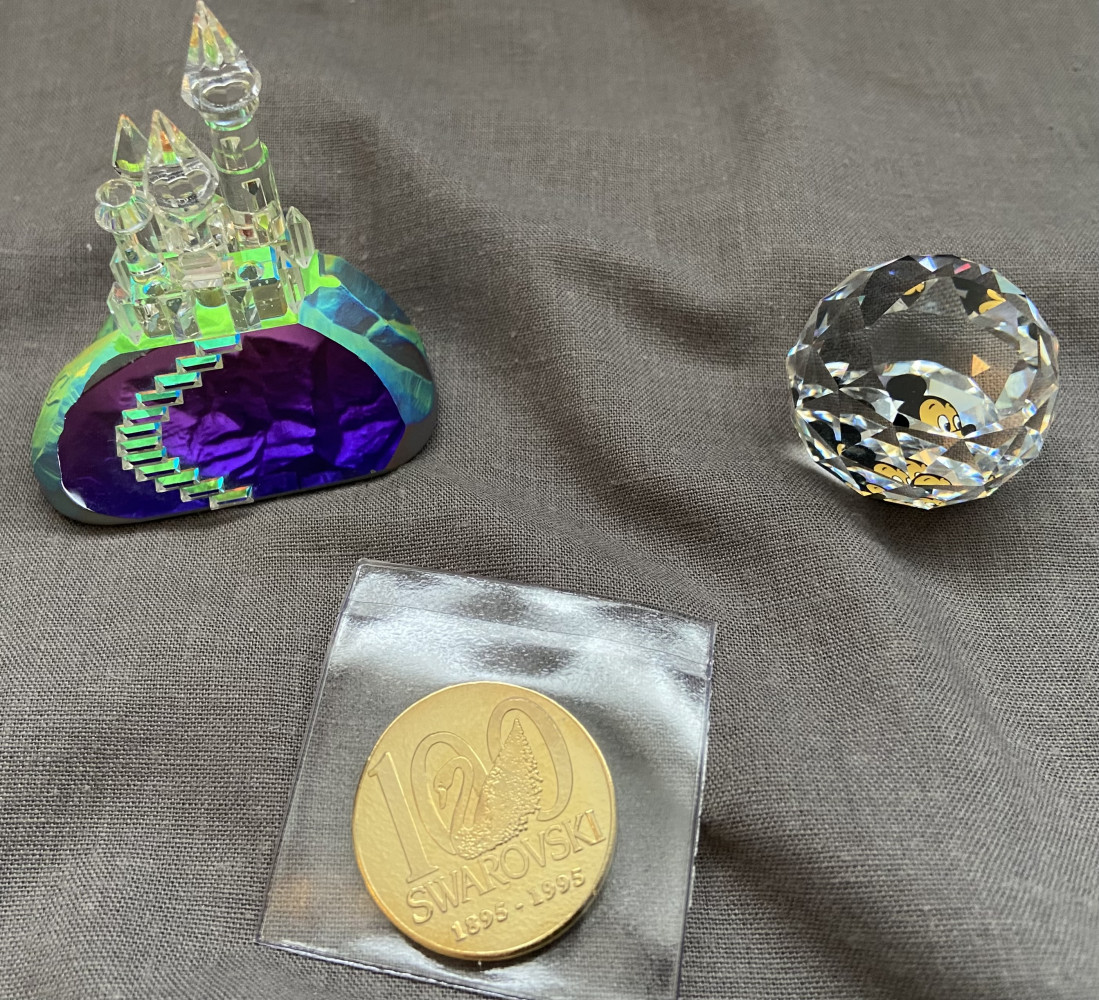 Swarovski 100 year members anniversary coin, small Swarovski crystal paperweight featuring Mickey Mouse, and Crystal castle