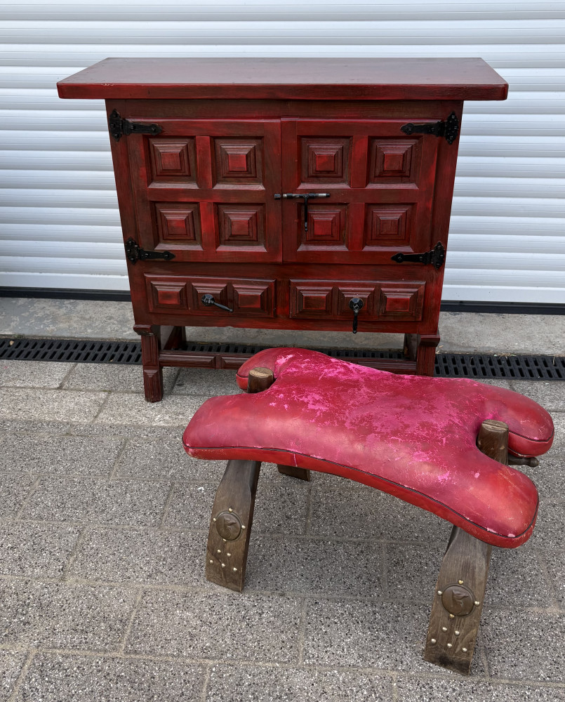 Red painted sideboard cabinet featuring a panelled door design and black iron hardware And camel stool