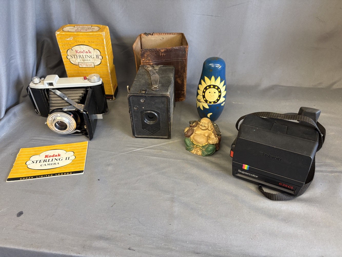 Antique box camera, vintage Kodak in original box and instant camera, and a buddha and set of Russian dolls