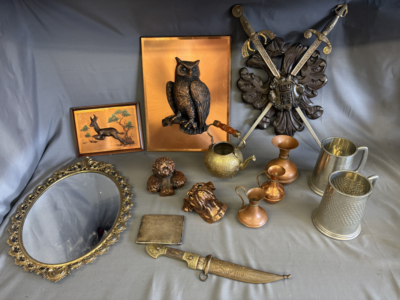 Collection of vintage decorative and utility items made of metal, including a large brass or copper owl wall plaque, an ornate oval mirror, pewter tankards, and various brass or copper vessels and figurines
