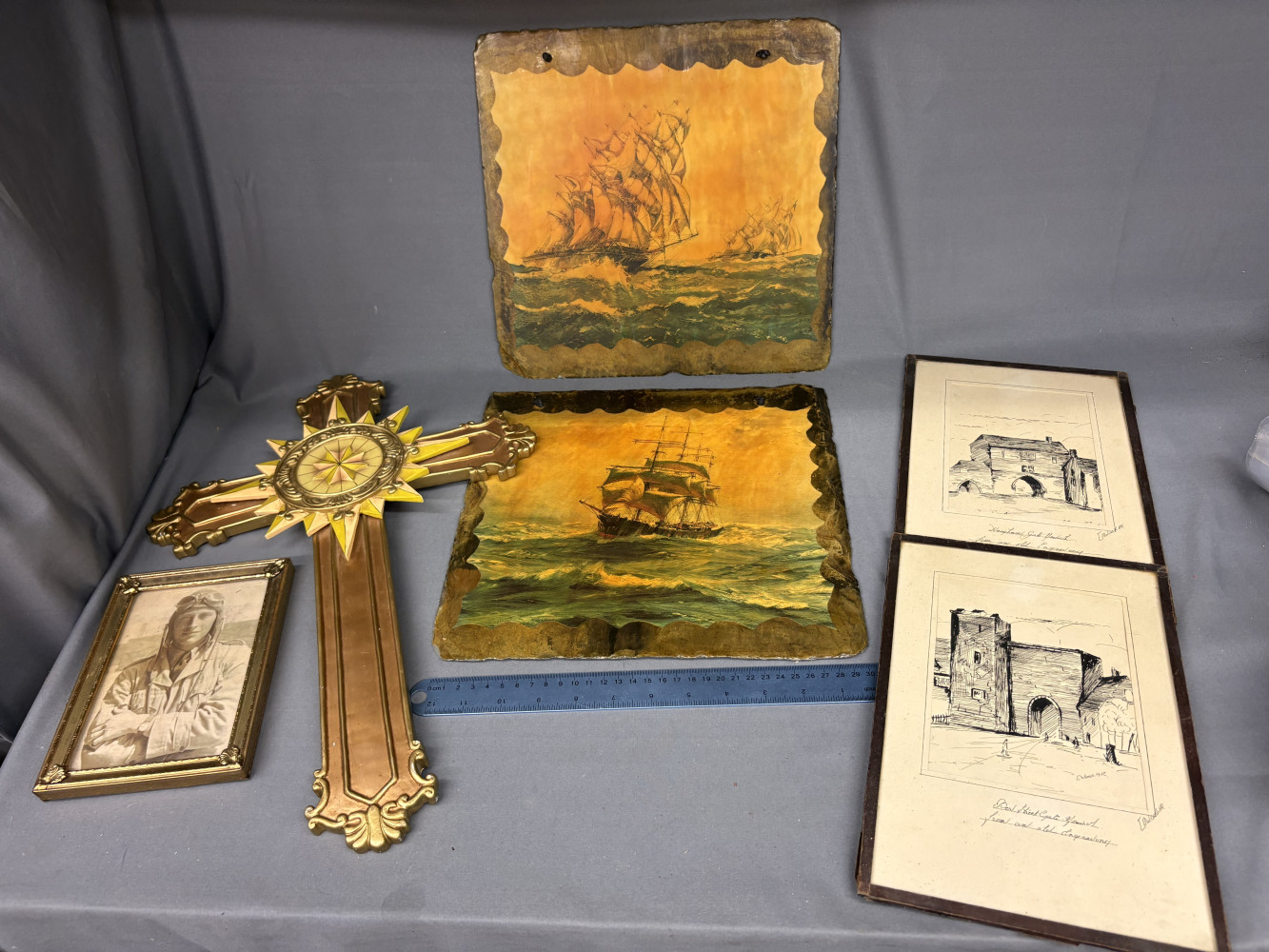 Collection of vintage decorative items, including two decoupage or painted slate plaques depicting sailing ships at sea, an ornate golden wall cross with a compass motif, a small framed portrait of an aviator in a cap, and 2 framed architectural pictures