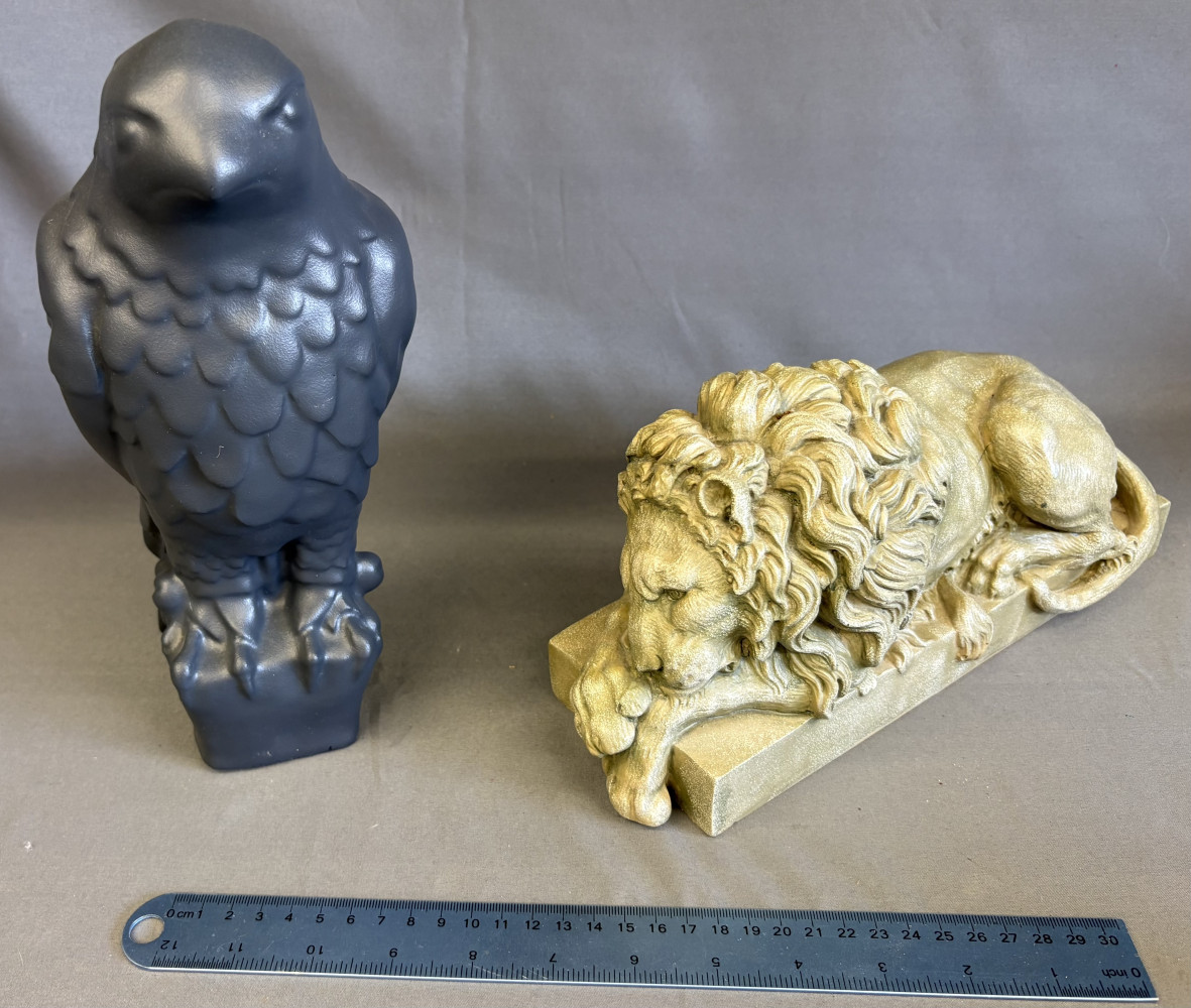 Grey Maltese Falcon statue and recumbent lion sculpture A/F as has a crack, modeled in the neoclassical style after the famous Vatican/Canova lions