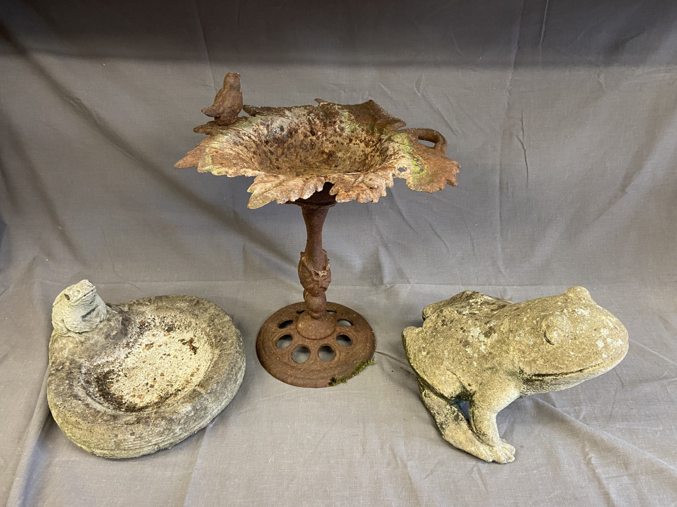 Cast iron bird feeder and two stone garden ornaments